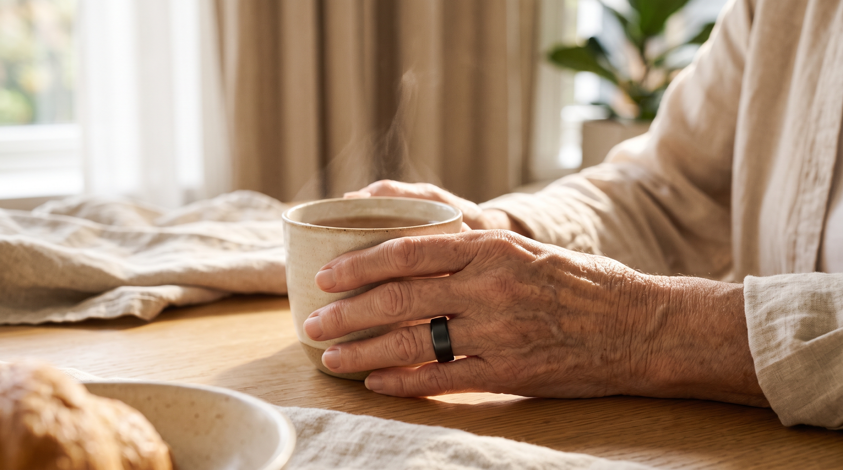Mãos de uma pessoa idosa segurando uma xícara enquanto usa um anel escuro